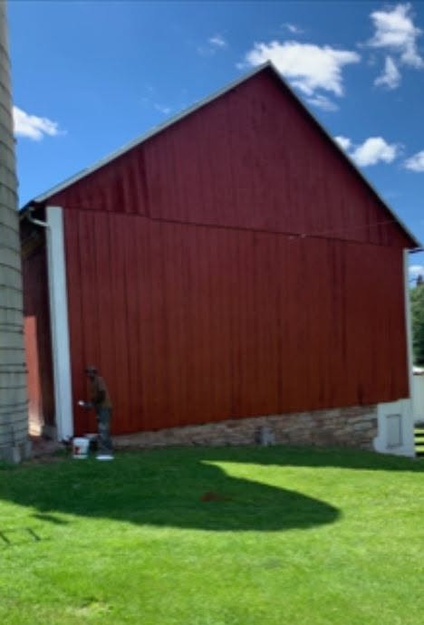 Faded barn siding restored with deep red protective coating