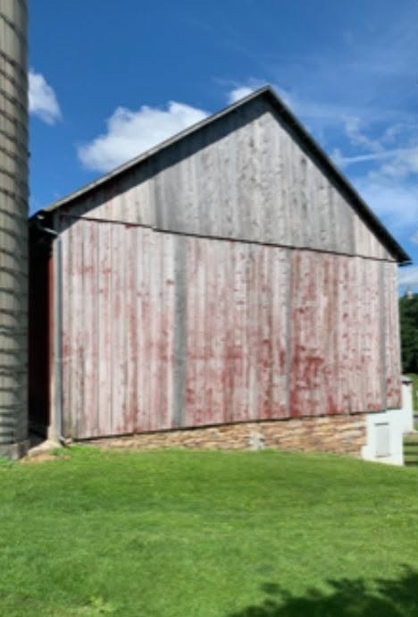 Before — Faded barn siding restored with deep red protective coating